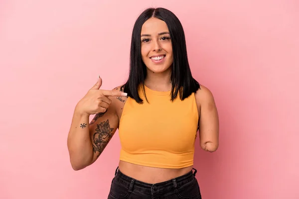 Young caucasian woman with one arm isolated on pink background person pointing by hand to a shirt copy space, proud and confident