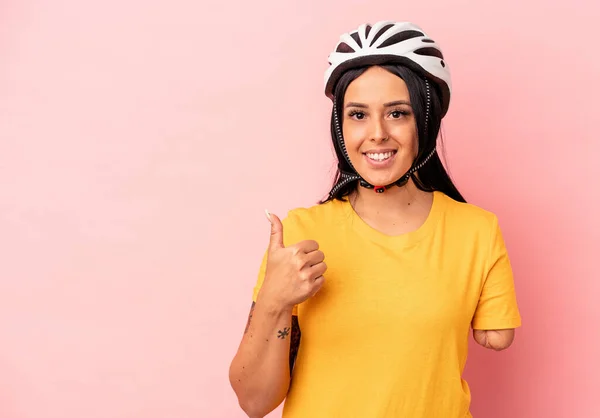 若いですCaucasian女性とともに一本の腕身に着けています自転車ヘルメットピンクの背景笑顔と上げ親指アップ — ストック写真