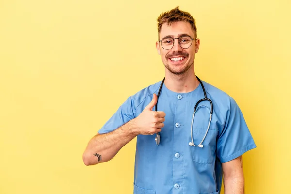 Joven Enfermera Caucásico Hombre Aislado Amarillo Fondo Sonriendo Levantando Pulgar —  Fotos de Stock