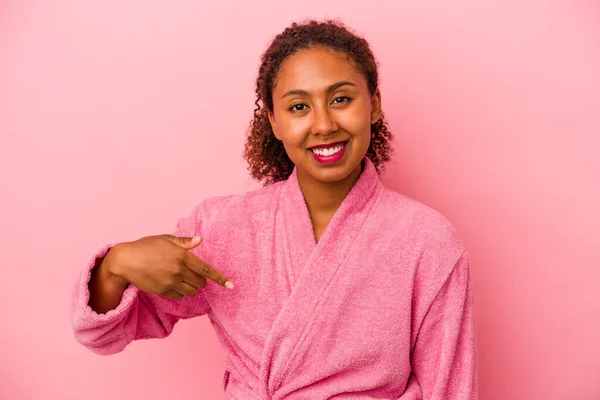 穿着浴衣的年轻的非洲裔美国女人 与粉色背景的人隔离开来 手指衬衫的复制品空间 自豪而自信 — 图库照片