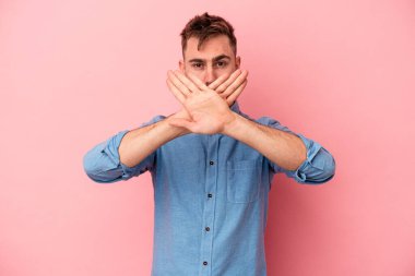 Pembe arka planda izole edilmiş genç beyaz adam inkar jesti yapıyor.