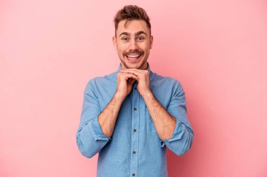 Pembe arka planda izole edilmiş genç beyaz adam şans için dua ediyor, hayrete düşüyor ve ağzını açıp önüne bakıyor..