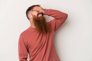 Beyaz arka planda uzun sakallı beyaz tenli genç beyaz adam ellerini başının üstünde tutarak neşeyle gülüyor. Mutluluk kavramı.