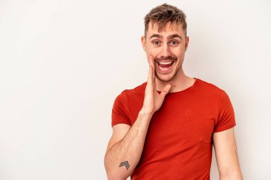 Beyaz arka planda izole edilmiş genç beyaz bir adam iki parmağını da kaldırıyor, gülümsüyor ve kendinden emin..
