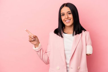 Tek kollu beyaz bir kadın pembe arka planda izole edilmiş gülümseyen ve işaret eden boş alanda bir şey gösteriyor..