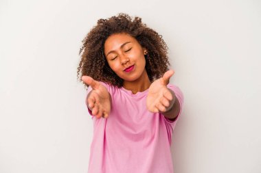 Beyaz arka planda izole edilmiş kıvırcık saçlı, dudakları kıvrık ve hava öpücüğü yollamak için avuç içleri tutan Afro-Amerikalı genç bir kadın..