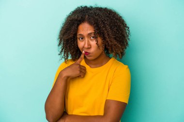 Mavi arka planda izole edilmiş kıvırcık saçlı, genç Afro-Amerikalı bir kadın. Bir strateji planlıyor, nasıl bir iş kurulacağını düşünüyor..