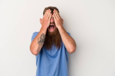 Beyaz arka planda uzun sakallı beyaz tenli genç beyaz adam yüzünün yarısını palmiye ile kaplayarak eğleniyor..