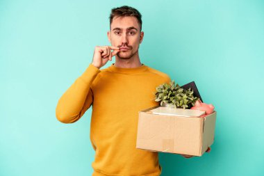 Kafkasyalı genç adam mavi arka planda izole edilmiş bir hareket yapıyor parmakları dudaklarında bir sır saklıyor..