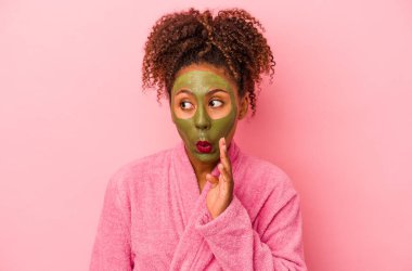 Pembe arka planda, bornoz ve yüz maskesi takan Afro-Amerikalı genç bir kadın gizli bir sıcak fren haberinin olduğunu ve kenara baktığını söylüyor.