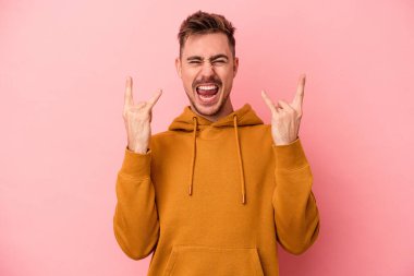 Pembe arka planda izole edilmiş genç beyaz adam boynuzlarını devrim konsepti olarak gösteriyor..