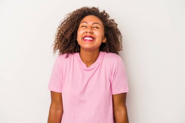 Beyaz arka planda yalıtılmış kıvırcık saçlı genç Afro-Amerikalı kadın gülüyor ve gözlerini kapıyor, rahatlamış ve mutlu hissediyor..