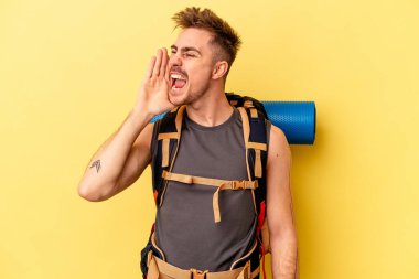 Genç yürüyüşçü beyaz adam sarı arka planda izole edilmiş bağırıyor ve avuç içini açık tutuyor..