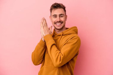 Pembe arka planda izole edilmiş genç beyaz adam enerjik ve rahat hissediyor, ellerini ovuşturuyor..