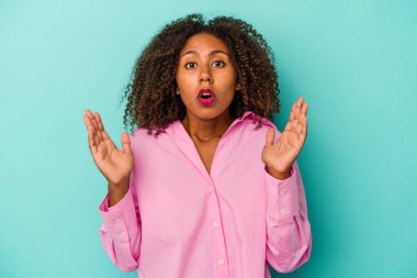 Mavi arka planda yalıtılmış kıvırcık saçlı, genç Afro-Amerikan kadının bir fikri var, ilham verici bir kavram..