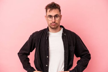 Pembe arka planda soyutlanmış, kafası karışmış, şüpheli ve kararsız genç bir beyaz adam..