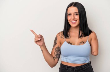 Beyaz arka planda tek kollu, beyaz tenli genç bir kadın gülümsüyor ve boş alanda bir şeyler gösteriyor..