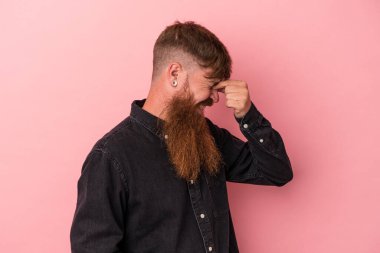 Kafkasyalı, uzun sakallı, pembe arka planda yaşayan, başı ağrıyan, yüzünün ön kısmına dokunan genç, beyaz bir adam..