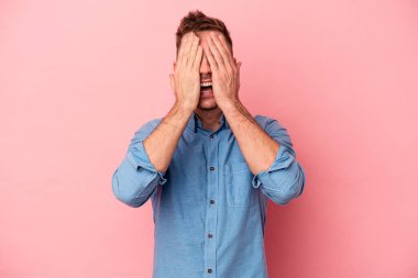 Pembe arka planda izole edilmiş genç beyaz adam yüzünün yarısını palmiye ile örterek eğleniyor..