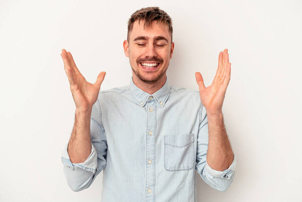 Young caucasian man isolated on white background smiling and showing a heart shape with hands.