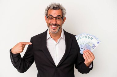 Elinde mavi arka plandaki banknotlar tutan orta yaşlı bir iş adamı gömlek fotokopi alanını elle işaret ediyor, gururlu ve kendinden emin.