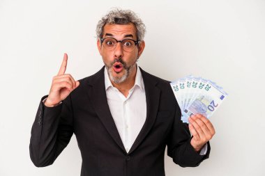 Elinde banknotlar tutan orta yaşlı bir iş adamı mavi arka planda bir fikri, ilham verici bir konsepti var..