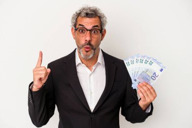 Elinde banknotlar tutan orta yaşlı bir iş adamı, mavi arka planda harika bir fikri, yaratıcılık kavramını barındırıyor..