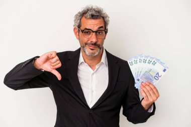 Orta yaşlı bir iş adamı mavi arka planda izole edilmiş banknotlar tutuyor. Sevmediği bir jesti gösteriyor. Anlaşmazlık konsepti.