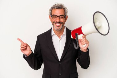 Orta yaşlı bir iş adamı beyaz arka planda izole edilmiş bir megafon tutuyor gülümsüyor ve boş alanda bir şeyler gösteriyor..