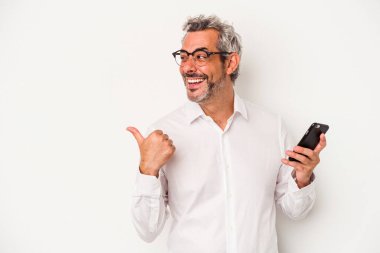 Orta yaşlı beyaz iş adamı beyaz arka plan noktalarında izole edilmiş bir cep telefonu tutuyor. Baş parmak uzakta, gülüyor ve kaygısız..