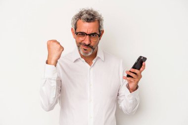 Beyaz arka planda izole edilmiş cep telefonu tutan Kafkasyalı iş adamı yumruğunu kameraya gösteriyor, agresif yüz ifadesi..