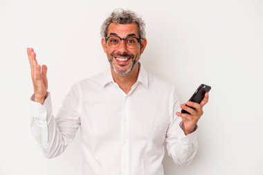 Beyaz arka planda izole edilmiş bir cep telefonu tutan Kafkasyalı iş adamı hoş bir sürpriz alıyor, heyecanlı ve el kaldırıyor..