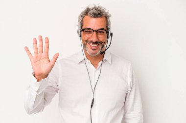 Beyaz arka planda izole edilmiş orta yaşlı pazarlamacı beş numarayı parmaklarıyla gülümsüyor..