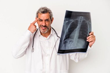 Beyaz arka planda izole edilmiş bir radyografi tutan orta yaşlı beyaz bir doktor işaret parmağıyla yaptığı hayal kırıklığını gösteriyor..