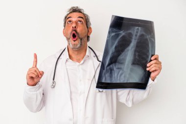 Beyaz arka planda izole edilmiş, ağzı açık, üst tarafı gösteren bir radyografi tutan orta yaşlı bir doktor..