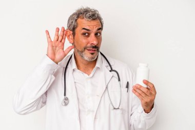 Beyaz arka planda izole edilmiş orta yaşlı doktor bir dedikoduyu dinlemeye çalışıyor..