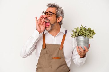 Beyaz arka planda izole edilmiş bir bitki tutan orta yaşlı bir bahçıvan. Avuç içiyle ağzını açmış bağırıyor..