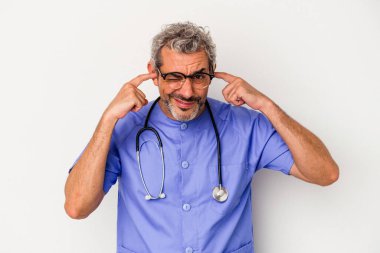 Beyaz arka planda izole edilmiş orta yaşlı beyaz bir adam kulaklarını elleriyle kapatıyor..