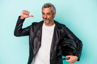 Mavi arka planda kask takan orta yaşlı motorcu beyaz adam gururlu ve kendinden emin hissediyor, örnek olarak..