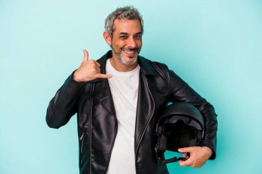 Mavi arka planda kask takan orta yaşlı beyaz bir adam cep telefonu hareketini parmaklarıyla gösteriyor..