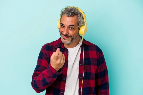 Medelålders Kaukasiska Mannen Lyssnar Musik Isolerad Blå Bakgrund Pekar Med — Stockfoto
