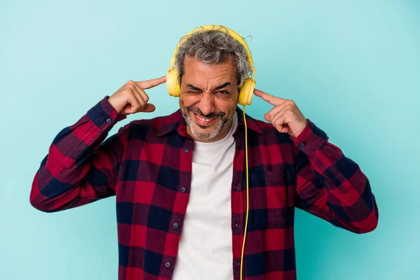Medelålders Kaukasisk Man Lyssnar Musik Isolerad Blå Bakgrund Täcker Öron — Stockfoto