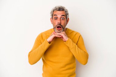 Beyaz arka planda izole edilmiş orta yaşlı beyaz bir adam şans için dua ediyor, şaşırmış ve ağzını açıp önüne bakıyor..