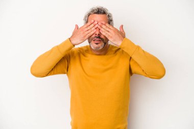Beyaz arka planda izole edilmiş orta yaşlı beyaz bir adam elleriyle gözlerini kapatmaktan korkuyor..