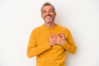 Beyaz arka planda soyutlanmış orta yaşlı beyaz bir adam gülüyor, elini kalbe koyuyor, mutluluk kavramını koruyor..