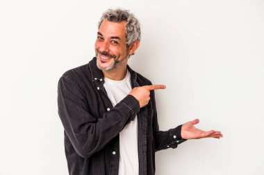 Beyaz arka planda izole edilmiş orta yaşlı beyaz bir adam palmiye üzerinde bir kopya alanı tutarken heyecanlı..