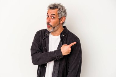 Beyaz arka planda izole edilmiş orta yaşlı beyaz bir adam gülümsüyor ve boş alanda bir şeyler gösteriyor..