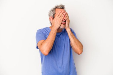 Beyaz arka planda izole edilmiş orta yaşlı beyaz bir adam elleriyle gözlerini kapatmaktan korkuyor..
