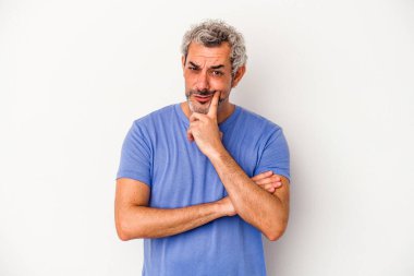 Beyaz arka planda izole edilmiş orta yaşlı beyaz bir adam şüpheli ve şüpheci bir ifadeyle yana bakıyor..