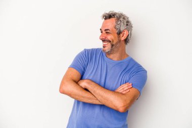 Beyaz arka planda izole edilmiş orta yaşlı beyaz bir adam kollarını kavuşturarak gülümsüyor..